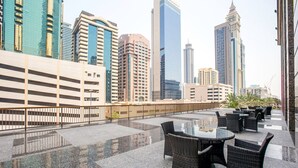 A rooftop terrace with outdoor seating and a city skyline view. - Blueground | DIFC, pool, nr Dubai Mall (Dubai)