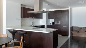 A modern kitchen with dark wood cabinets, a white countertop, and stainless steel appliances. - Blueground | DIFC, pool, nr Dubai Mall (Dubai)