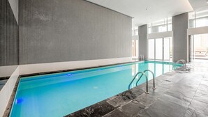 An indoor swimming pool with clear blue water, tiled walls, and a modern design. - Blueground | DIFC, pool, nr Dubai Mall (Dubai)