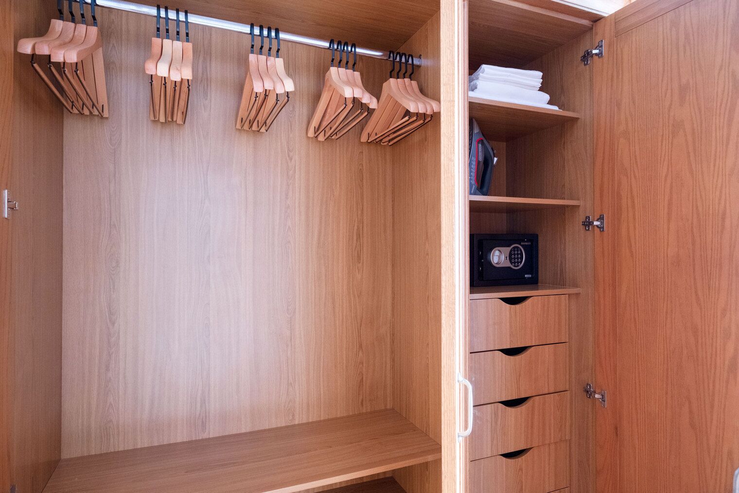 A wooden wardrobe with multiple compartments, including hanging space for clothes and drawers for storage.