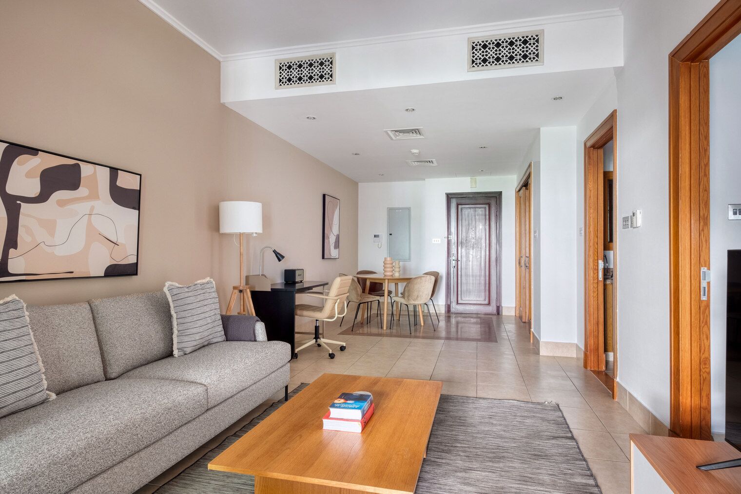 A modern living room with a sofa, coffee table, and a dining area with chairs and a table.