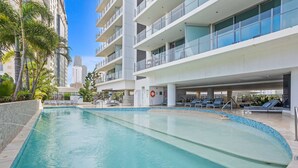 Un hotel moderno con una amplia piscina cubierta, varios balcones y vistas de edificios circundantes.