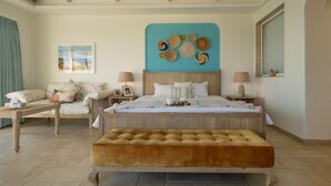 Een slaapkamer met een groot bed, een houten bankje, een sofa en een kunstwerk aan de muur.