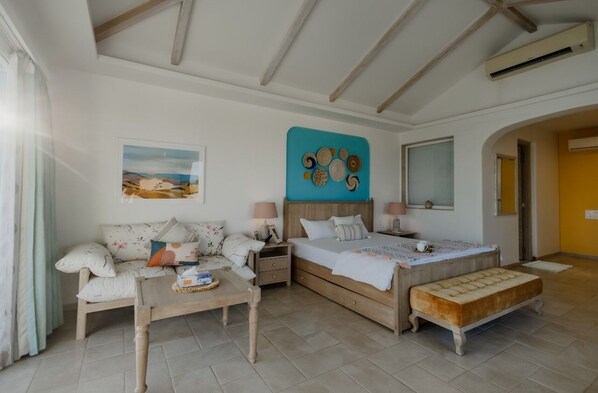 A bedroom with a bed, a sofa, a bedside table, and a bench.