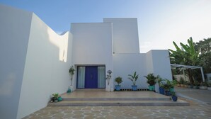 Een modern gebouw met een blauwe deur, witte muren en een betegeld entreegebied.