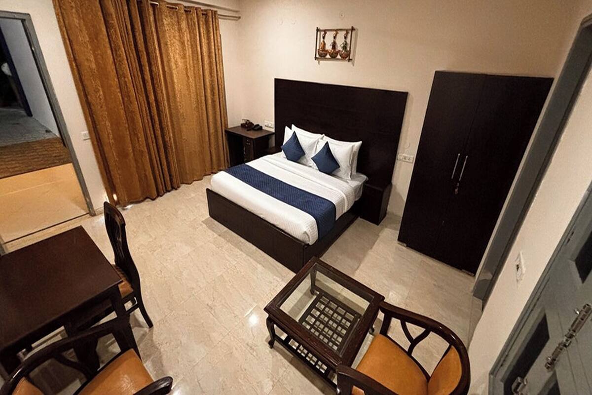Une chambre d’hôtel comprenant un lit, un bureau, une chaise, une petite table et une armoire.