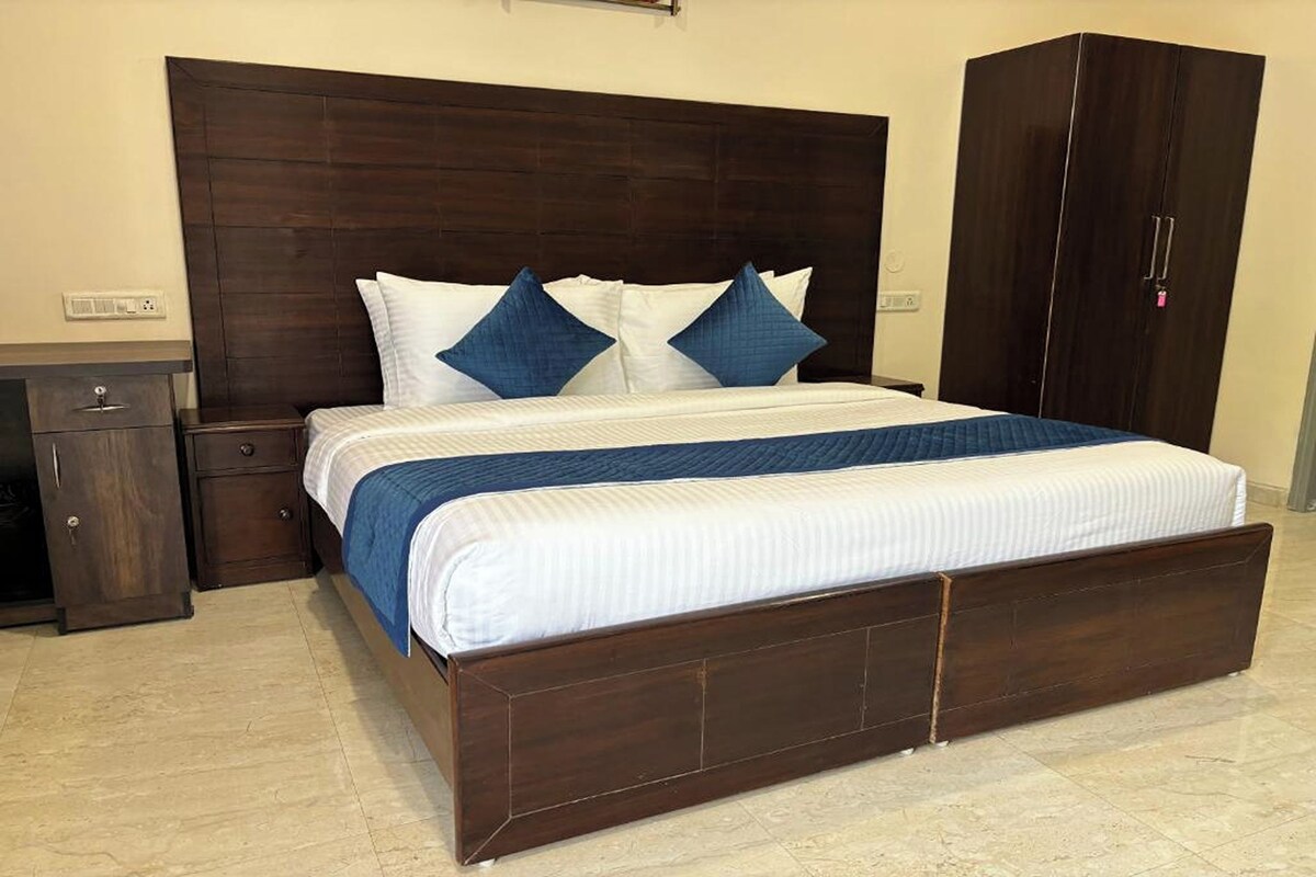 Ein Schlafzimmer mit dunklem Holzbett, weißer Bettwäsche und blauen Akzentkissen.