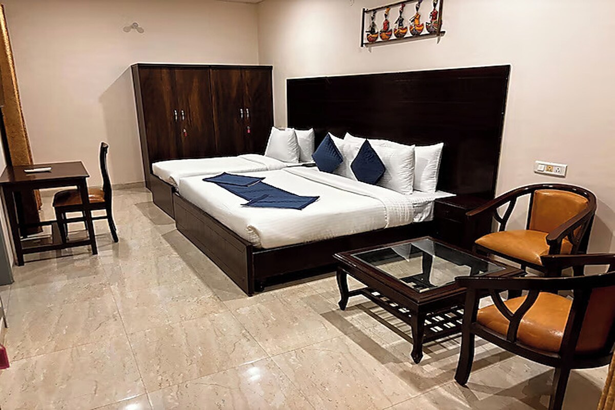 A hotel room with a bed, a desk, a chair, and a glass coffee table.