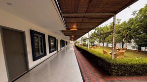 Un couloir d’hôtel avec une galerie couverte, un espace jardin doté de sièges extérieurs et une vue dégagée sur la façade de l’immeuble.