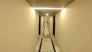 Egy hosszú, keskeny folyosó, a padlón geometrikus mintával, amely a végén lévő ajtóhoz vezet.