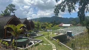 A resort with multiple wooden cabins, a central pathway, and a lush garden area. - Nirwana Kintamani (Kintamani)