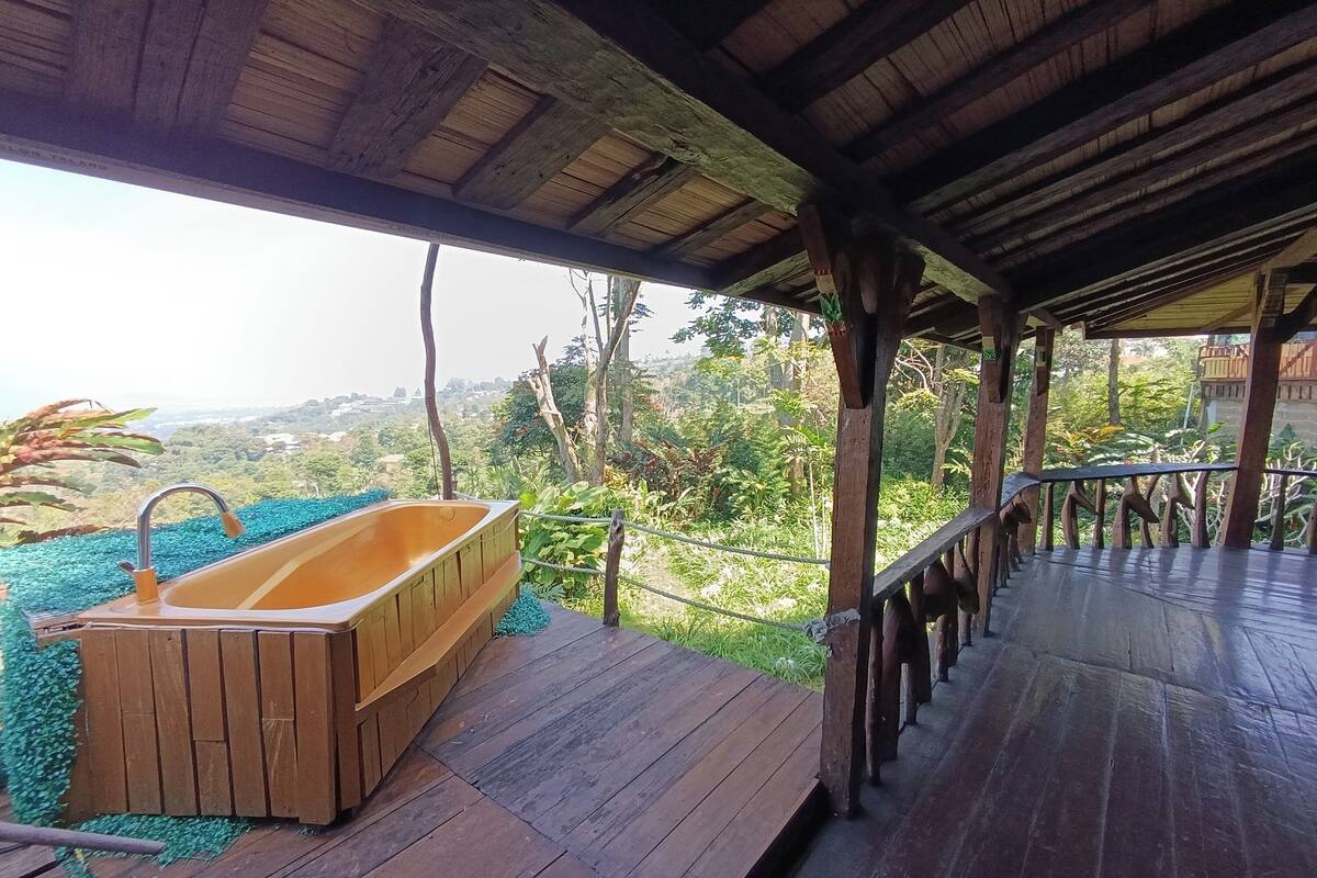 Eine Holzterrasse mit Whirlpool und Blick auf eine üppige Landschaft.