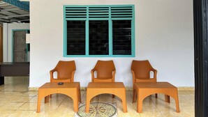 Ein Zimmer mit Fenster, drei Korbstühlen und Fliesenboden.