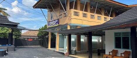 A building with a covered outdoor area, a signboard, and a gated entrance.