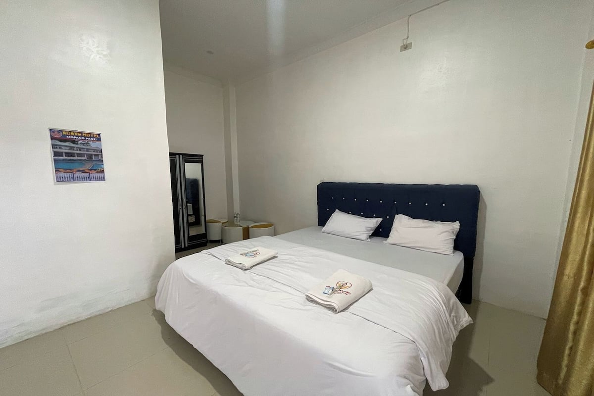 A hotel room with a large bed, two bedside tables, and a poster on the wall.