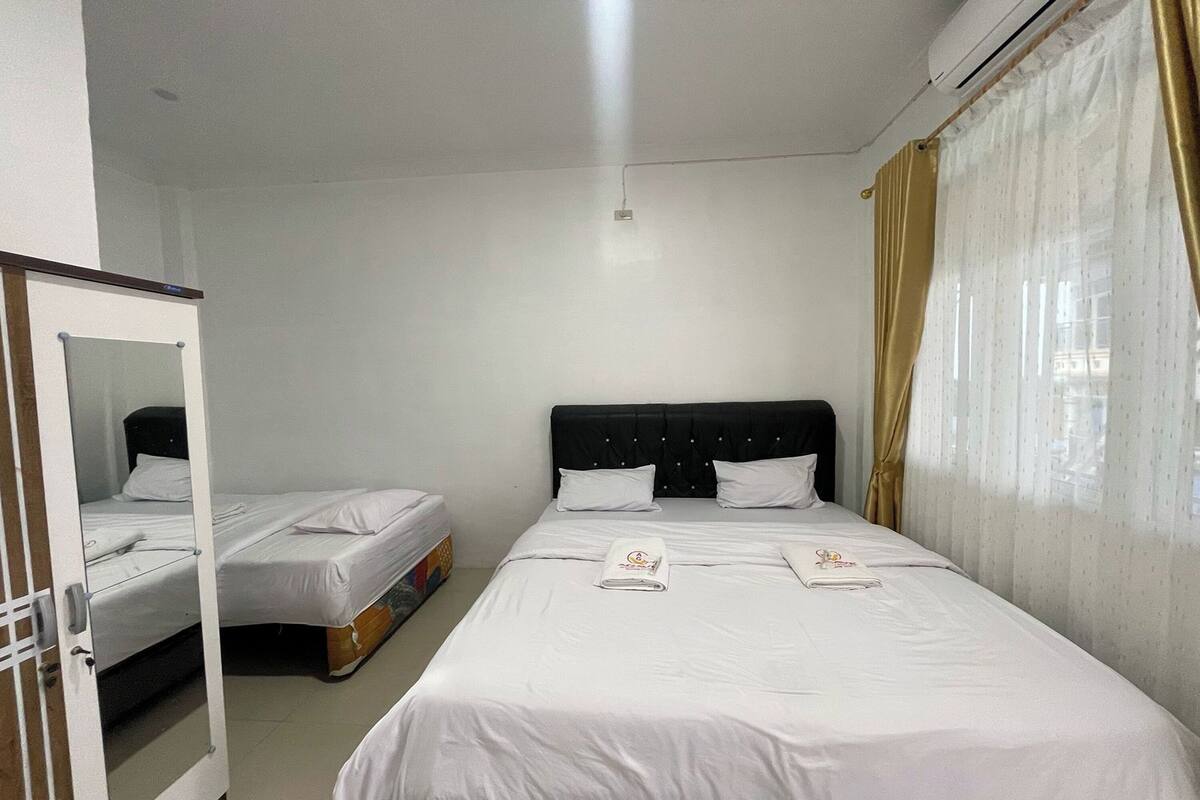 A hotel room with two beds, a wardrobe, and a mirror.