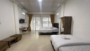 Une chambre d’hôtel avec deux lits, un bureau, une chaise et un téléviseur.