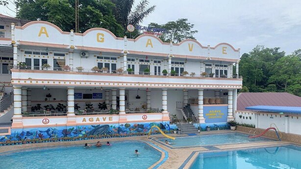 Un hôtel doté d’une piscine, d’un espace abrité et d’une enseigne sur laquelle on peut lire « AGAVE ».