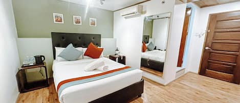 A bedroom with a bed, bedside table, and a mirror.