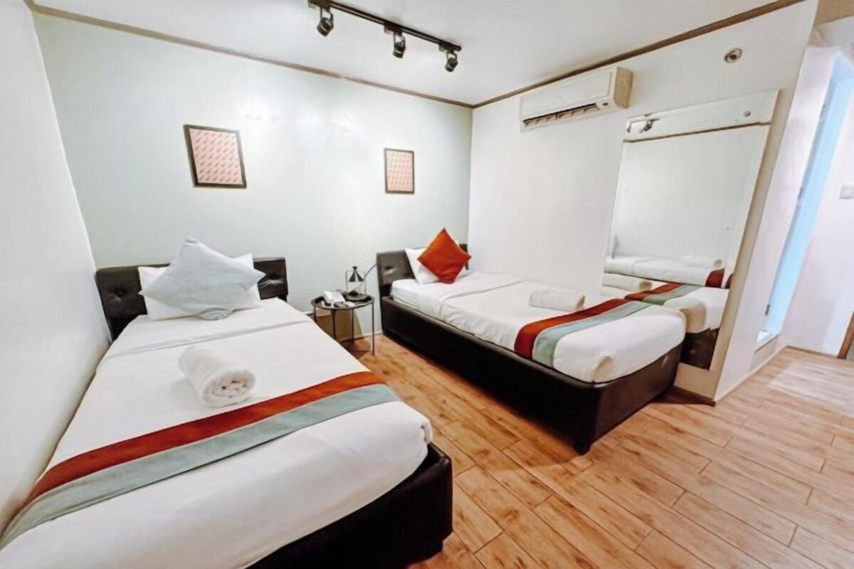 A hotel room with two beds, a mirror, and a small table with a lamp.