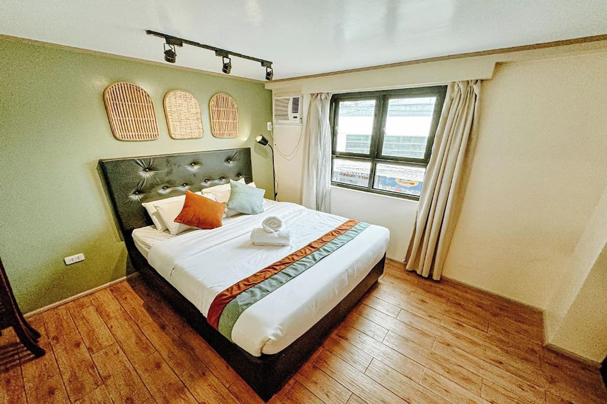 A neatly made bed with a headboard, a window with curtains, and a view of the outside.