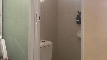 Un baño con inodoro, lavamanos y cabina de ducha de vidrio.