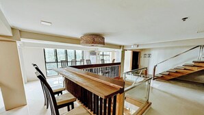 Een ruime eetruimte met een houten bank en stoelen, een glazen balustrade en een trap naar een ander niveau.