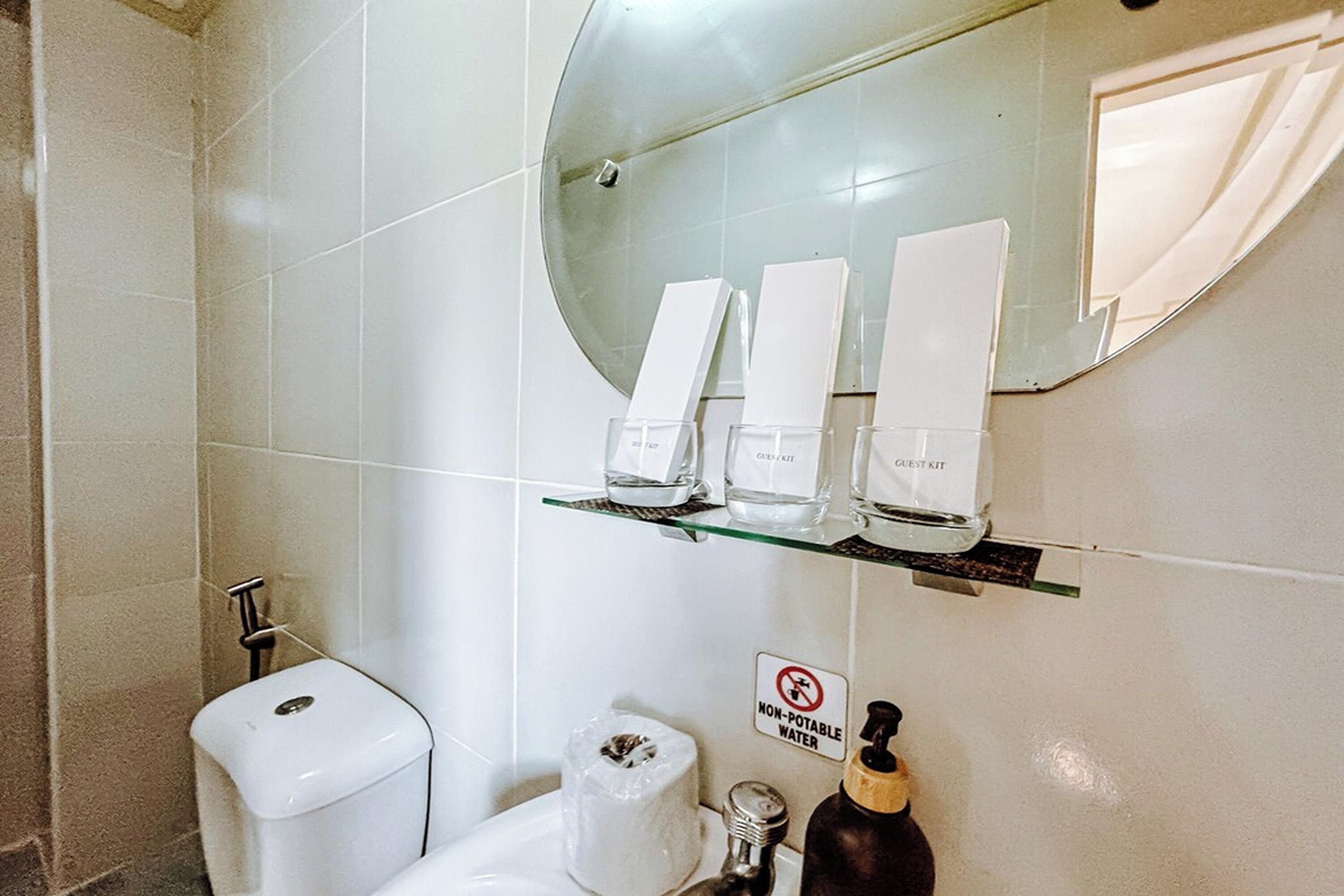 A bathroom with a toilet, a sink, a glass shelf with toiletries, and a 'Non-Potable Water' sign.