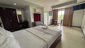 A hotel room with a large bed, a desk, a chair, and a small balcony area. - Yellowbell Hotel (Batangas City)