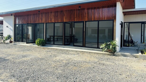 A modern building with a wooden facade, large glass doors, and potted plants. - Selline Bed And Breakfast (Bacnotan)