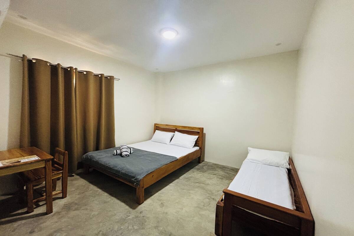 A small, clean room with a wooden bed, a desk, and a chair.
