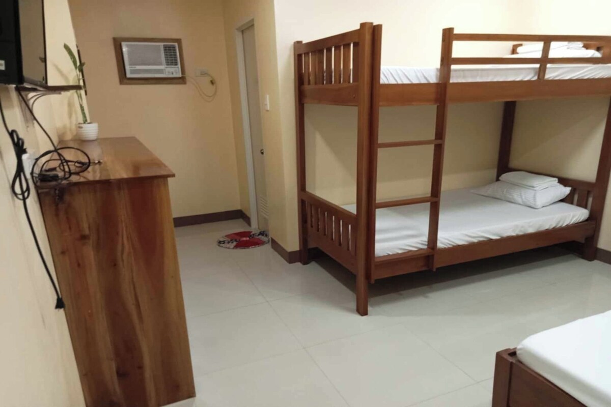 Quarto com beliche, escrivaninha de madeira e um pequeno vaso de planta.