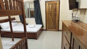 Un dormitorio con una cama litera de madera, un armario de madera, una puerta con panel decorativo y un televisor montado en la pared.