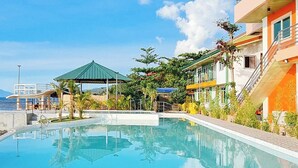 Una piscina con un pabellón, una escalera y vista al mar.
