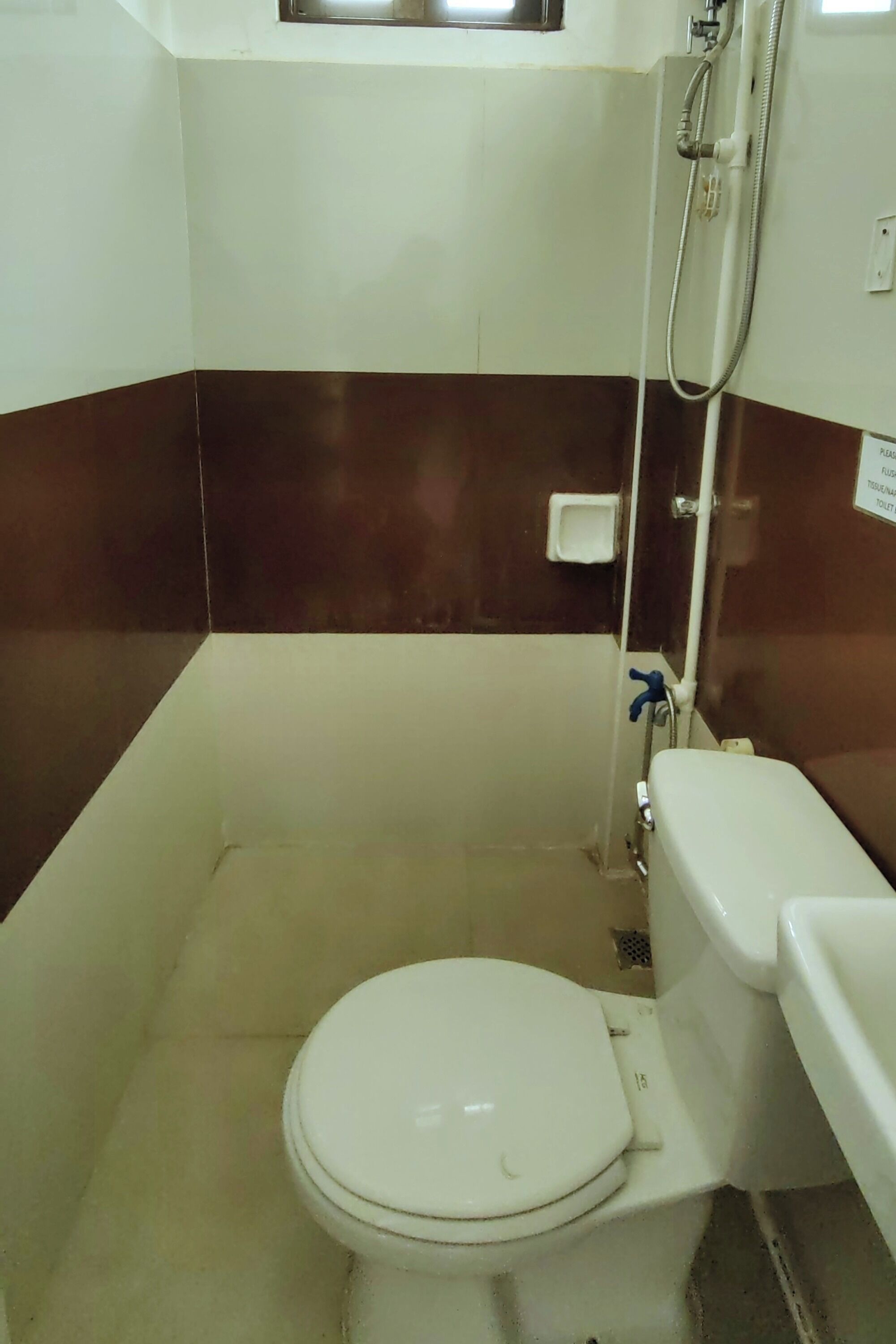 Un baño pequeño y funcional con inodoro blanco, ducha y lavamanos blanco.