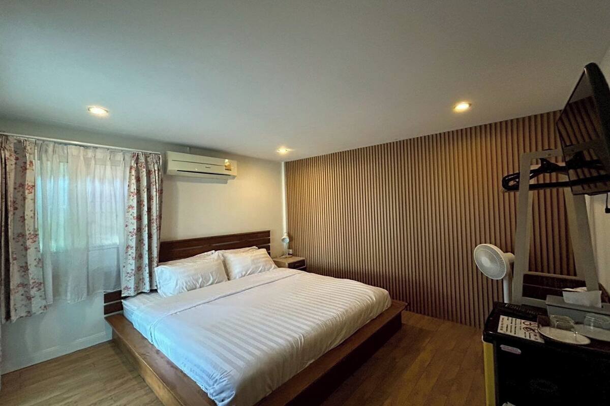 A bedroom with a bed, a nightstand, a mirror, and a wall-mounted air conditioner.