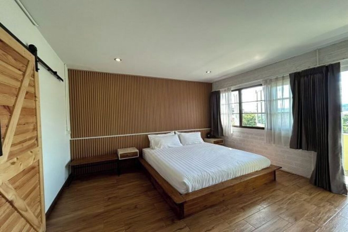 Une chambre moderne avec un lit en bois, une table de chevet et une fenêtre avec des rideaux.
