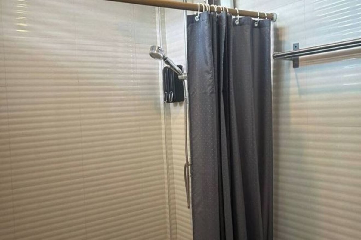 Zona de ducha con cabezal, toallero y cortina.