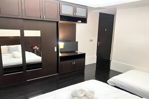 A hotel room with a bed, a TV, a wardrobe, and a door. - Bm Pool Villa Pattaya (Sattahip)