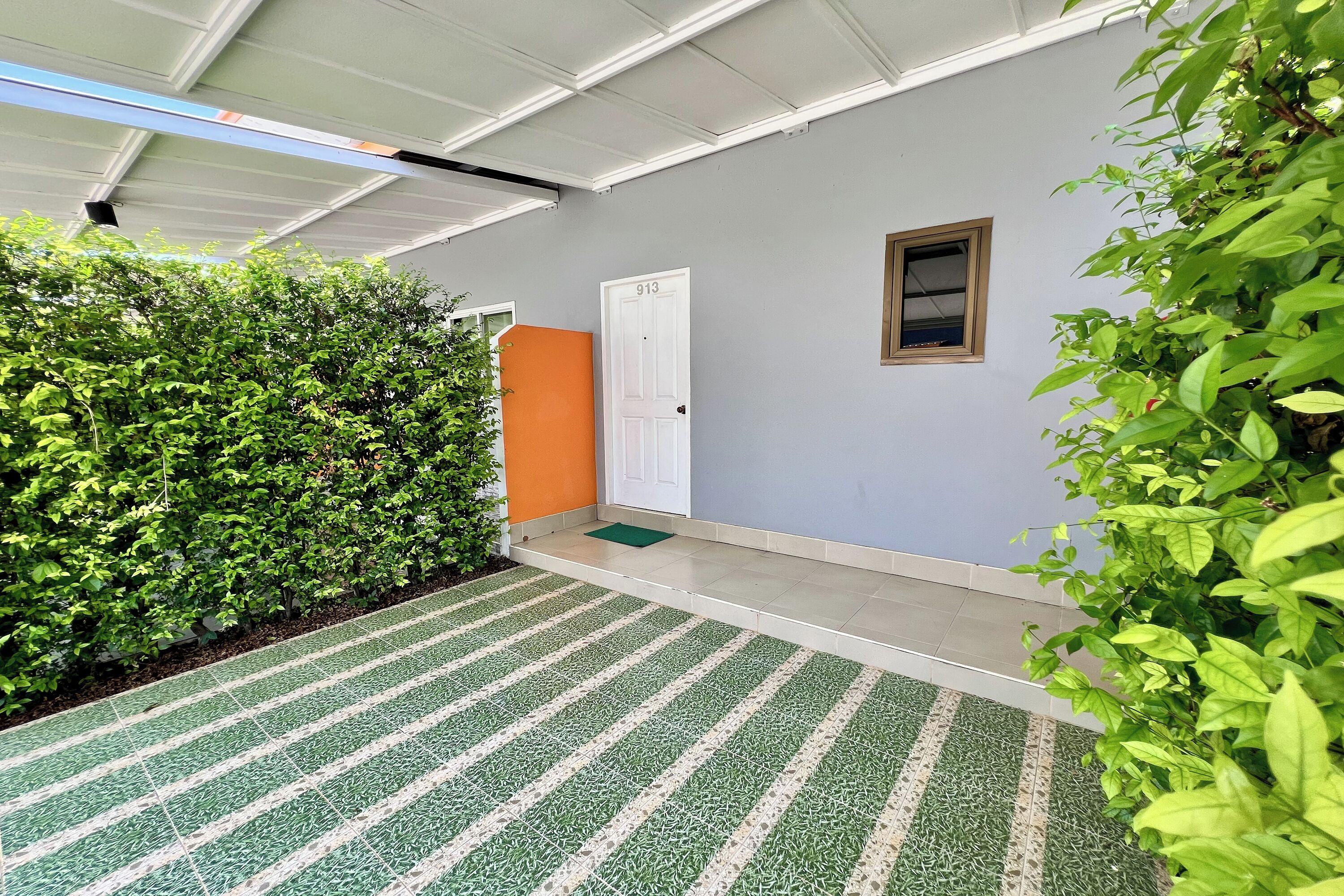 Un espacio al aire libre cubierto con un tapete verde y blanco a rayas que conduce a una puerta con el número 913.