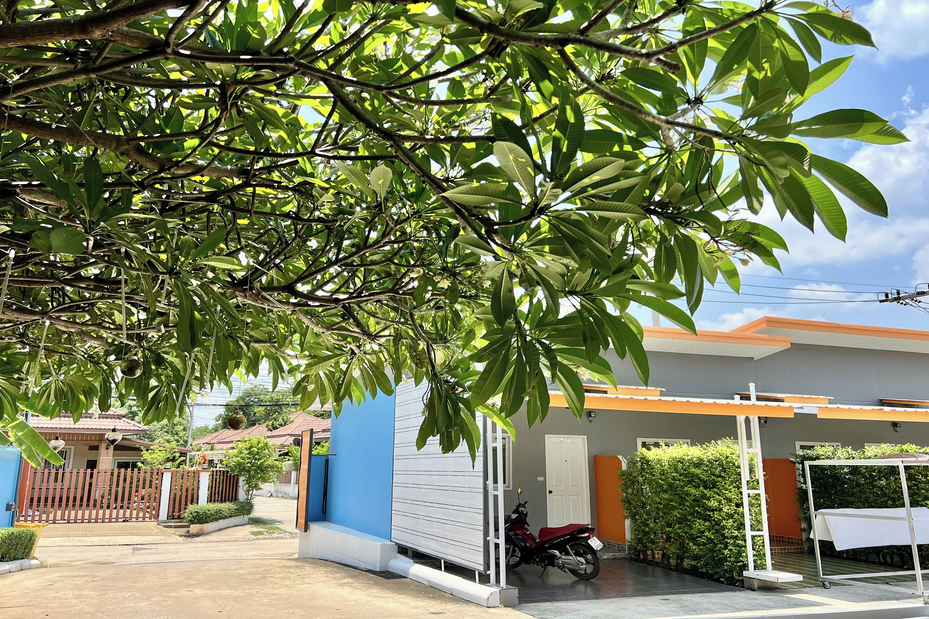 Un quartier résidentiel avec une maison bleue, une moto et une entrée fermée par un portail.