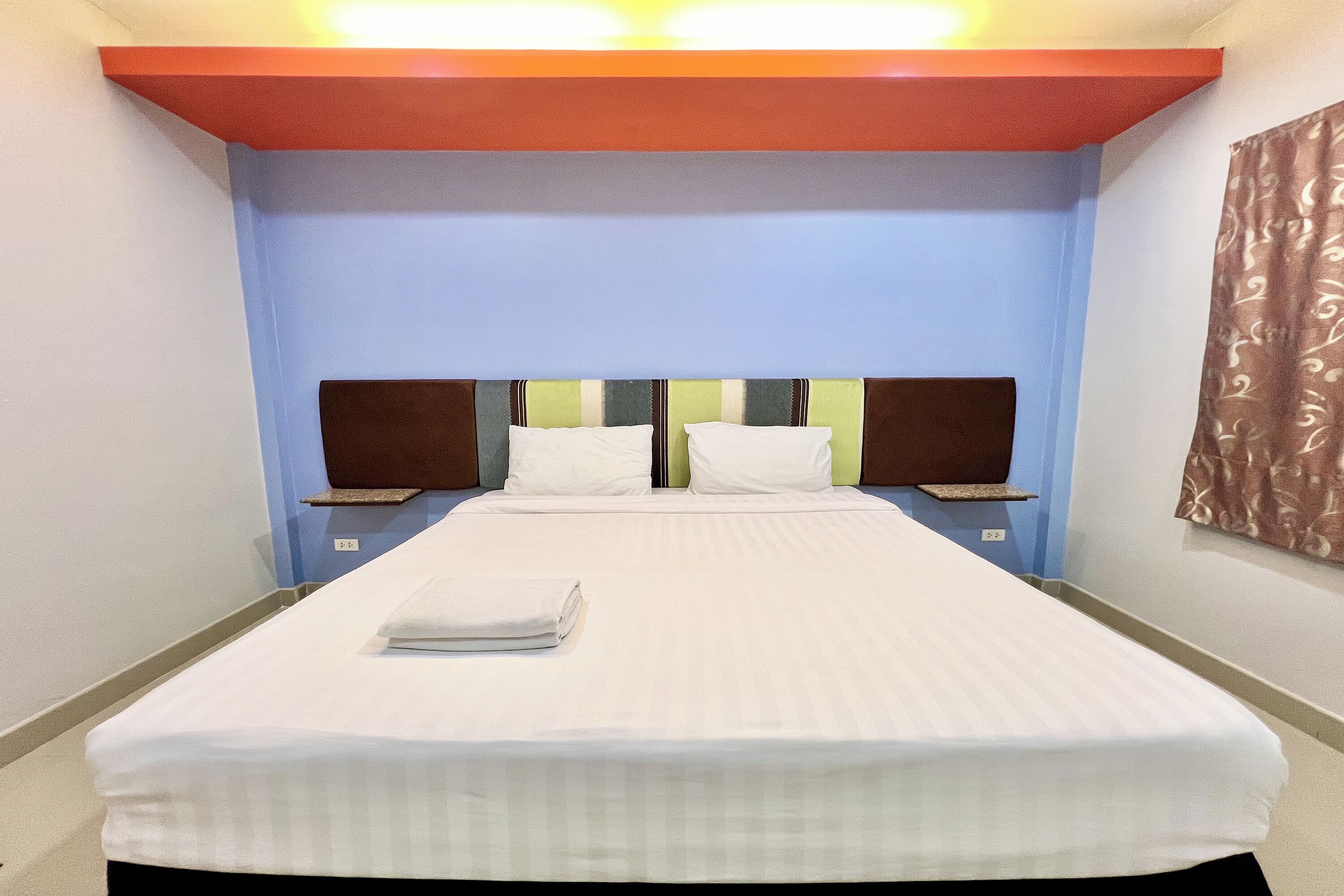 Habitación de hotel con una cama grande, dos mesitas de noche y un cabecero con estampado a rayas.