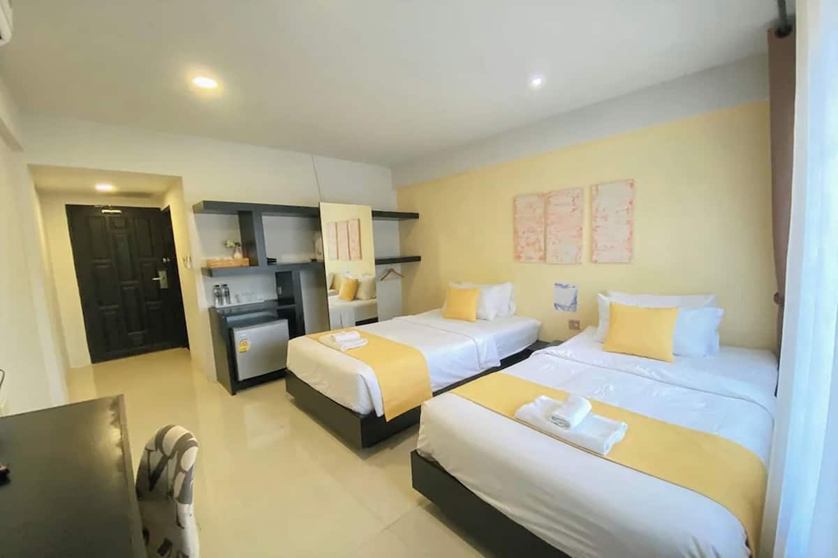 A hotel room with two beds, a desk, and a chair. There are two bedside tables with lamps.