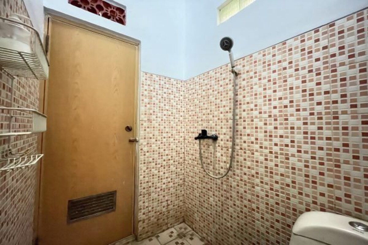 A small bathroom with a shower, a toilet, and a door.