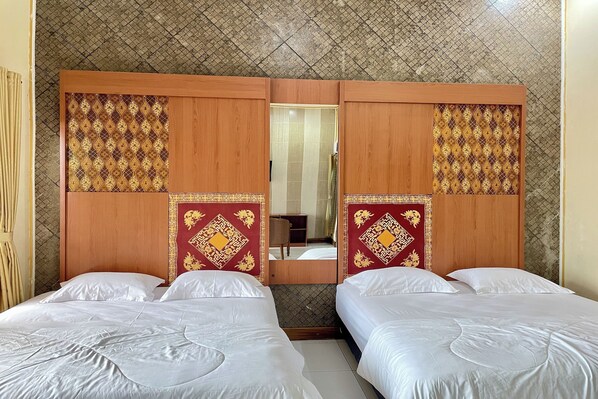 A hotel room with two beds, a wooden wardrobe with decorative panels, and a tiled ceiling. - Hotel Ramayana Garut (Garut)
