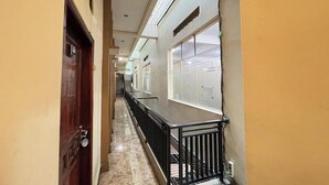 A corridor with a wooden door, a black railing, and a tiled floor. - Hotel Ramayana Garut (Garut)