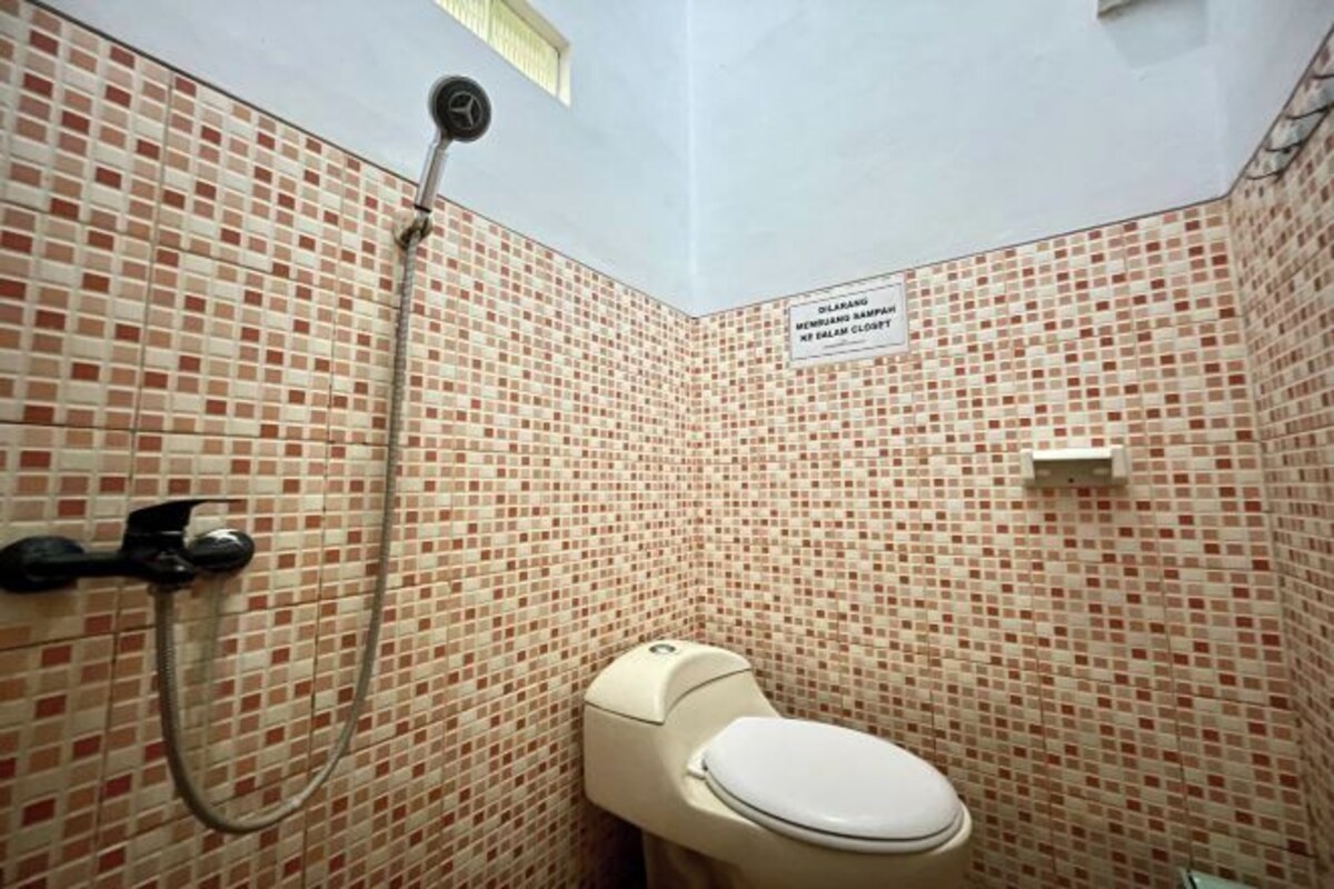 A bathroom with a toilet, a shower, and a tiled wall.