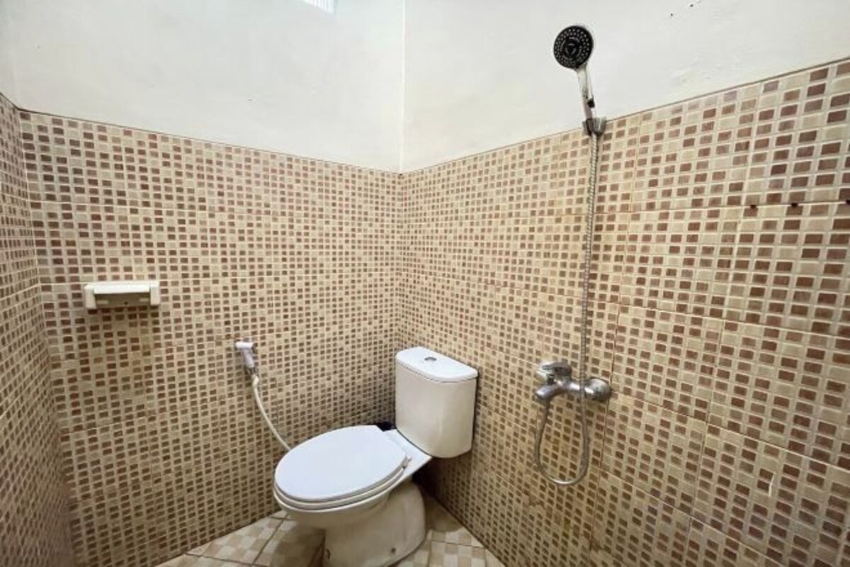 A small bathroom with a toilet, a shower, and tiled walls.