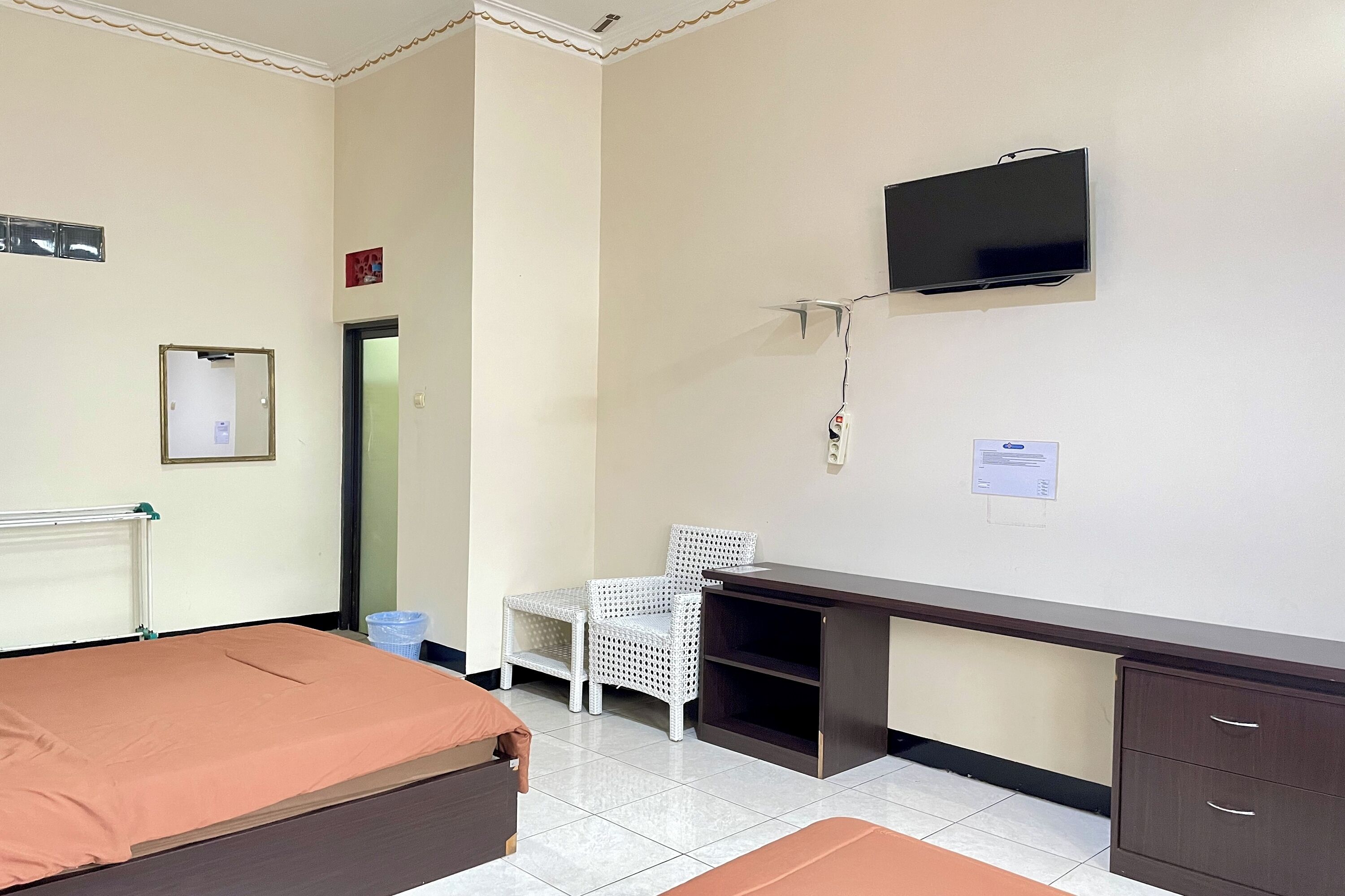 Una habitación de hotel con cama, escritorio, silla, televisor y armario.