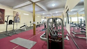 A gym with various exercise equipment, a red carpet, and mirrors on the walls. - Hotel Ramayana Garut (Garut)